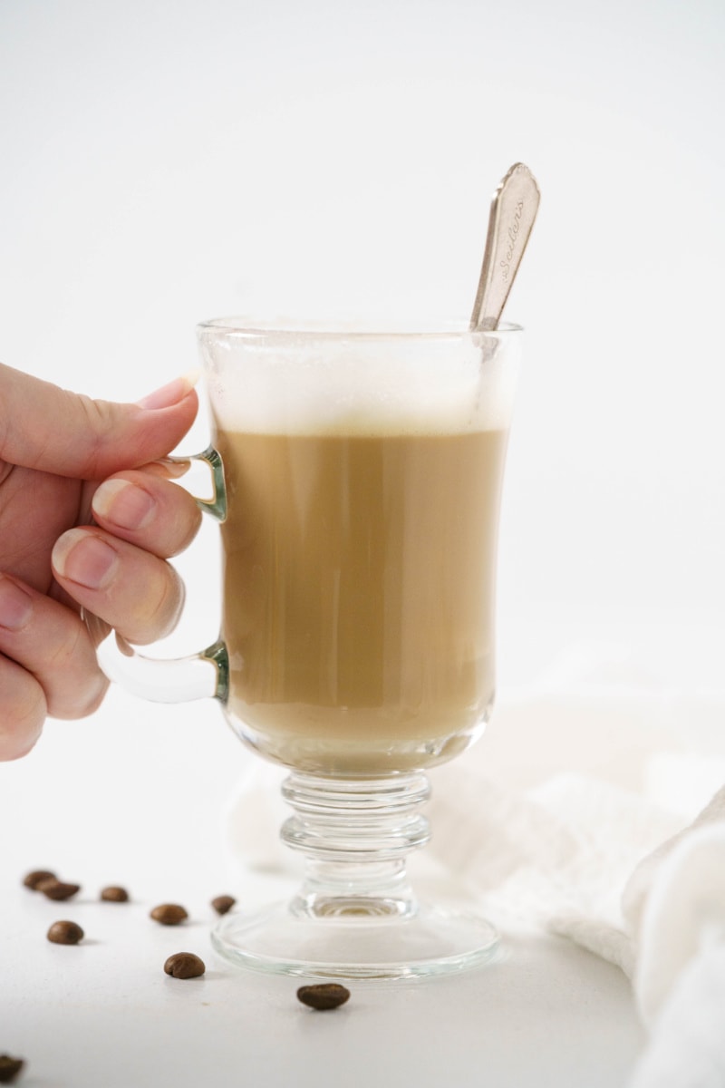 hand holding mug of vanilla latte