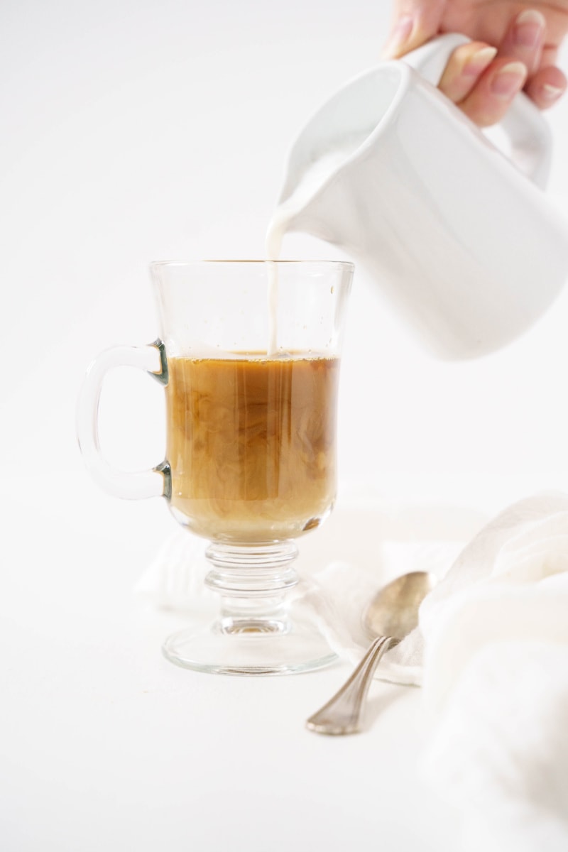 pouring milk into coffee in mug