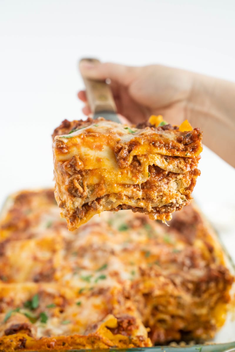 spatula scooping out one slice of lasagna out of pan