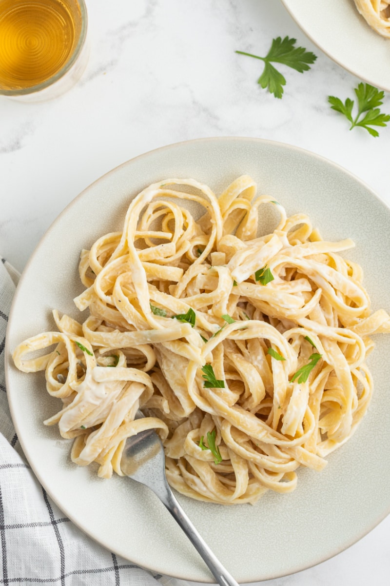 serving of fettuccine alfredo on white plate with fork