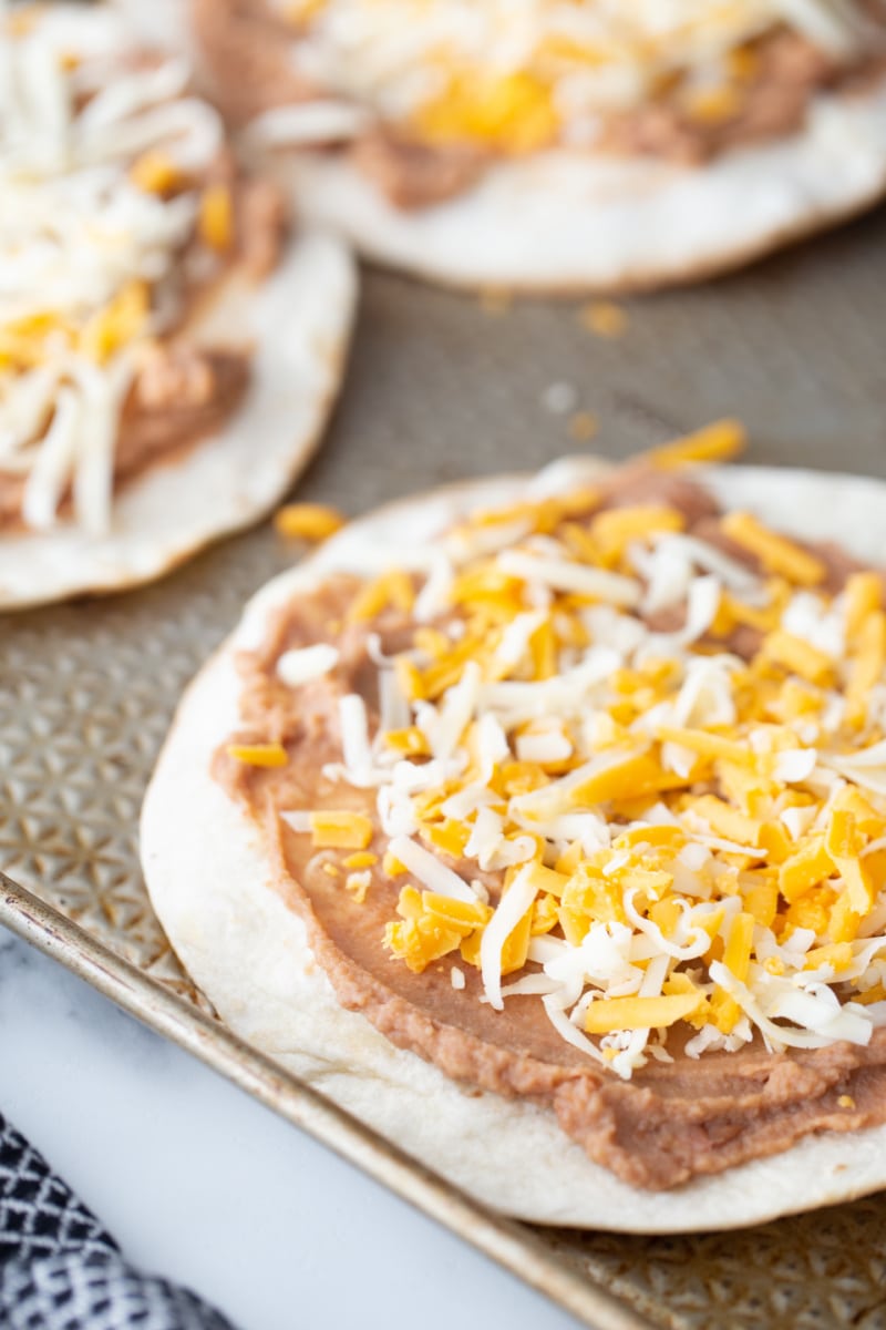 cheese and beans on a tortilla ready for oven