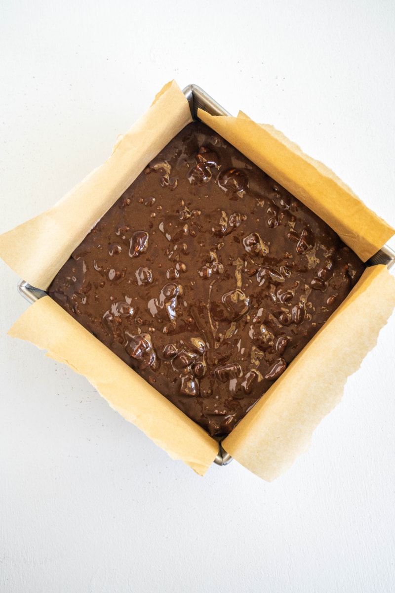 brownie batter in square pan ready for oven