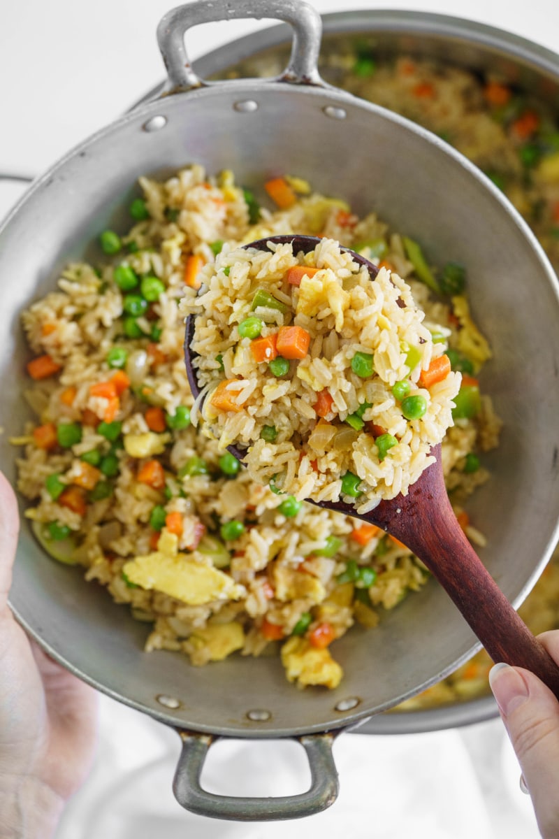 spoon holding up vegetable fried rice in skillet