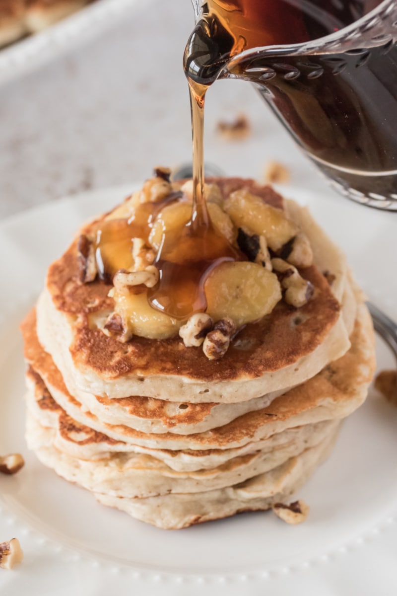 pouring syrup on stack of banana bread pancakes