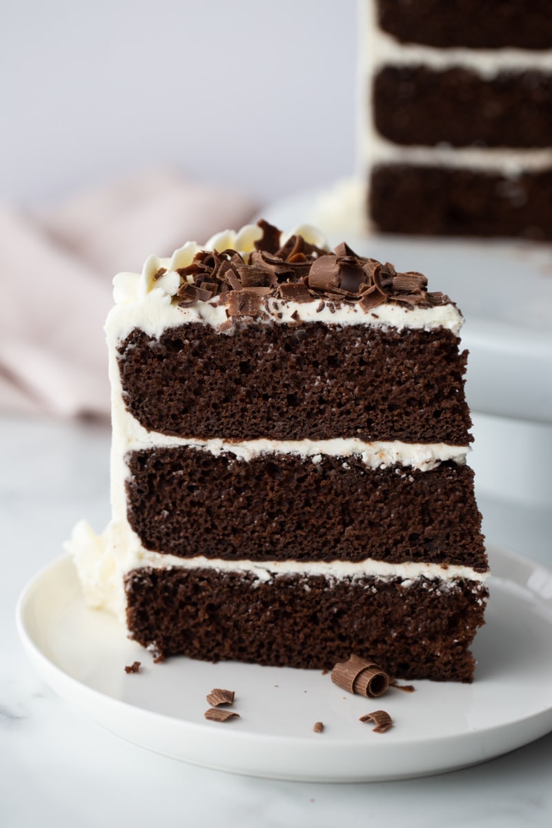 slice of three layer chocolate cake with white frosting