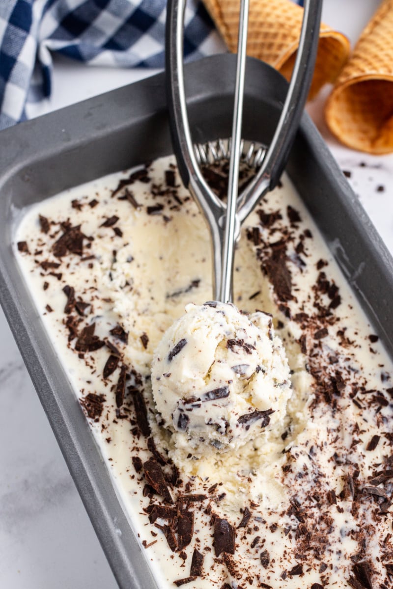 stracciatella gelato in a tub with an ice cream scoop of it scooped up