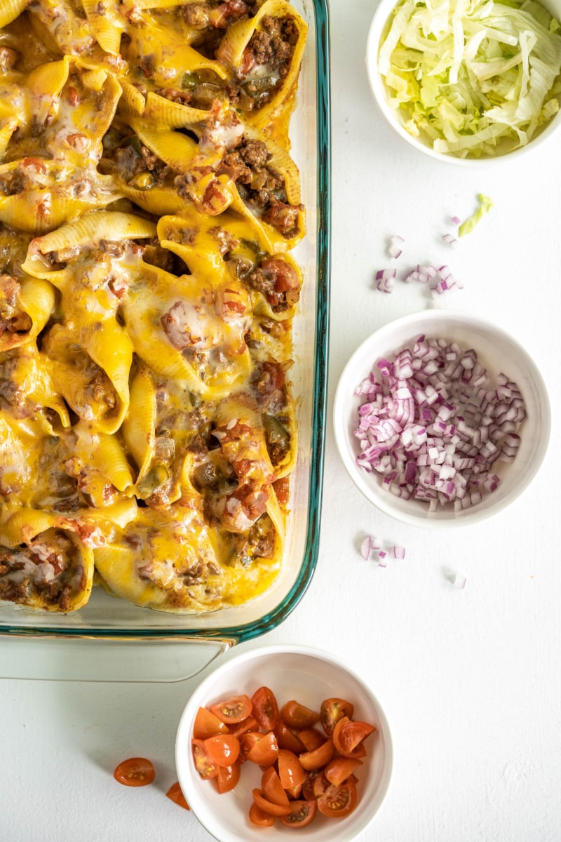 tacos stuffed shells in pyrex with fixings in bowls on side