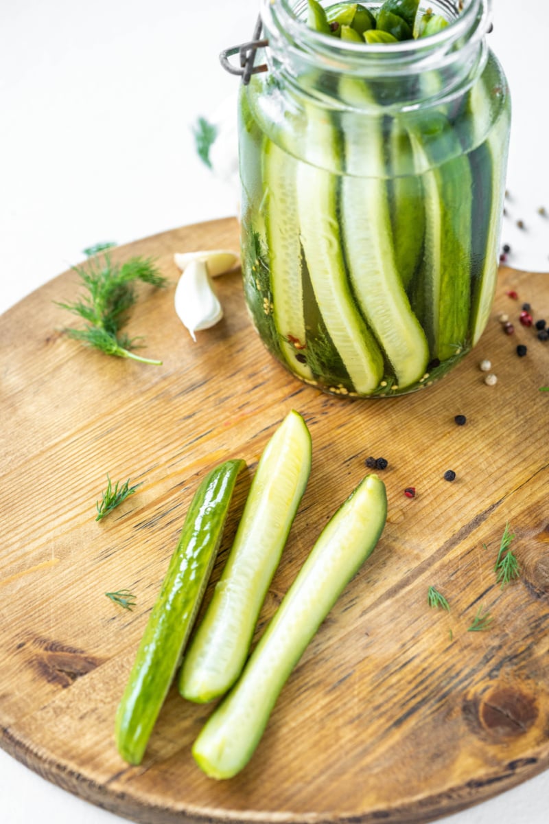 pickles in a jar and three pickles on cutting board