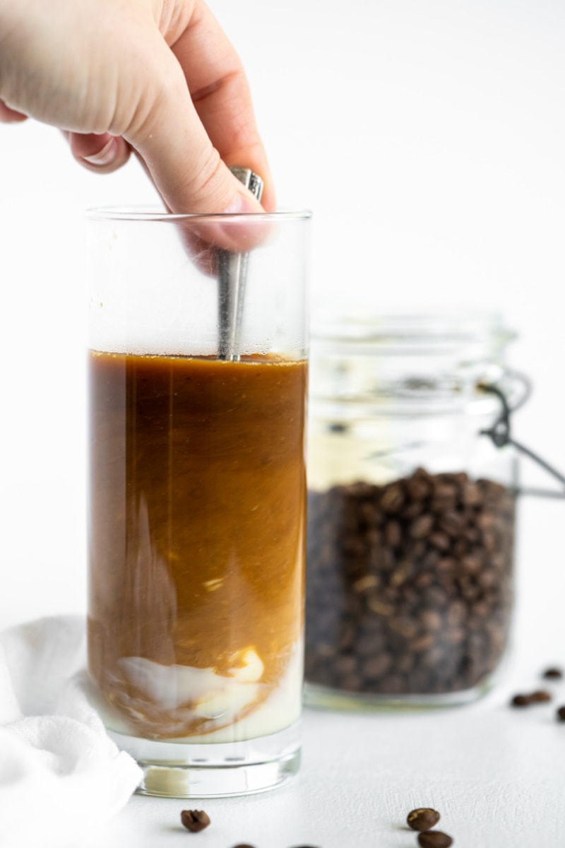 stirring iced coffee in a tall glass