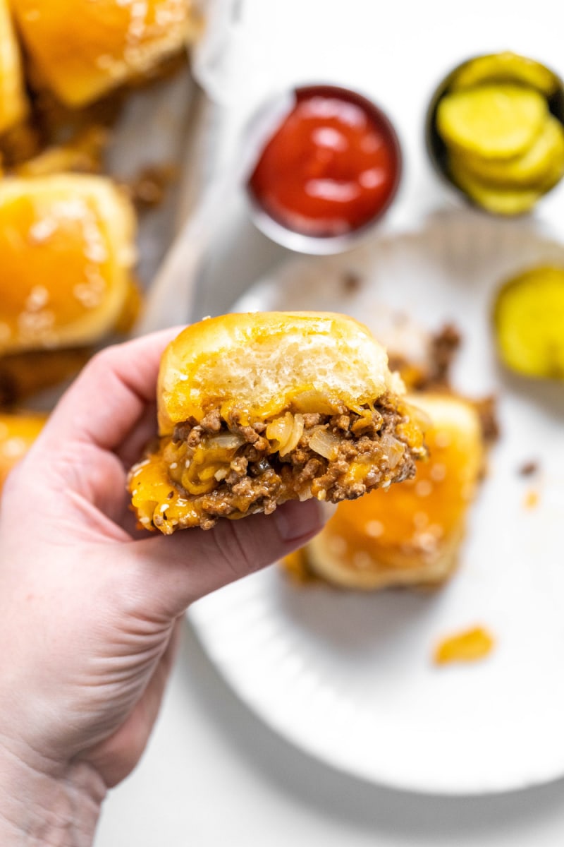 hand holding baked cheeseburger slider