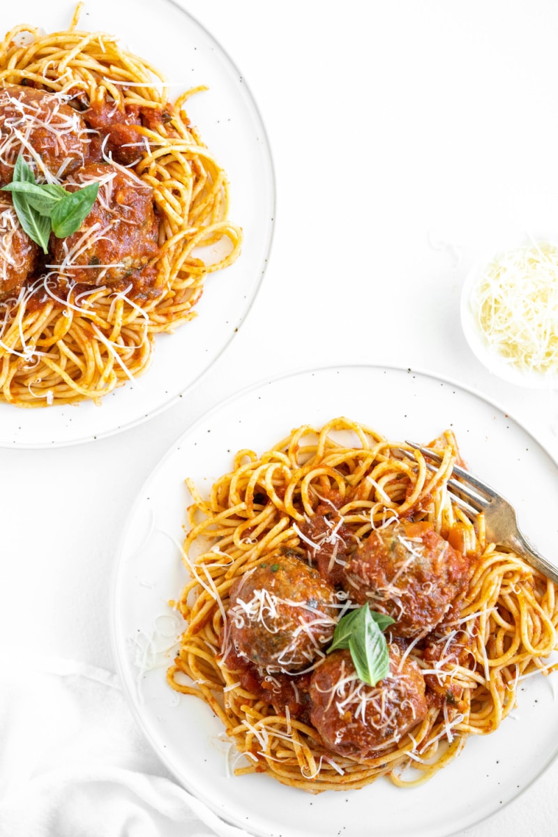 spaghetti and meatballs on two white plates