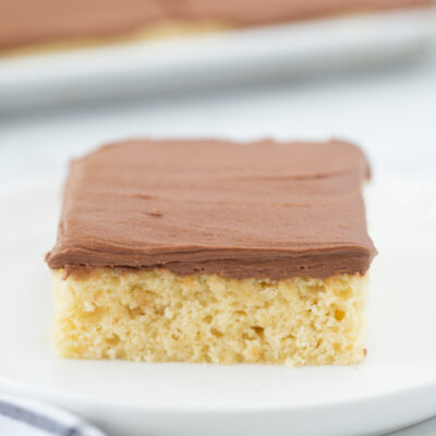 slice of yellow cake on a plate with chocolate frosting