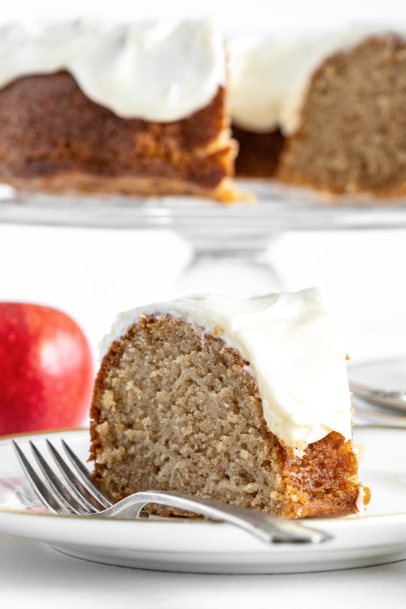 slice of apple cake with cream cheese frosting on plate
