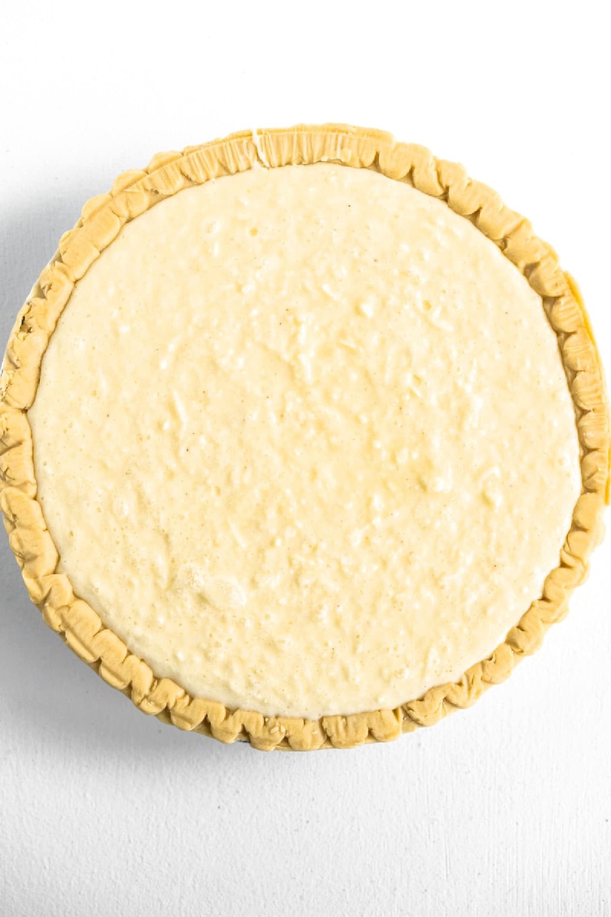 This Old Fashioned Coconut Custard Pie is rich, creamy and packed with sweet coconut flavor! 🥥 Made with a silky homemade custard and flaky pie crust, it's the perfect dessert for Thanksgiving, Easter, Christmas or Sunday dinner. Save this classic pie recipe! #coconutcustardpie #pierecipes #dessertrecipes #oldfashionedrecipes #holidaydesserts coconut cream pie ready for oven