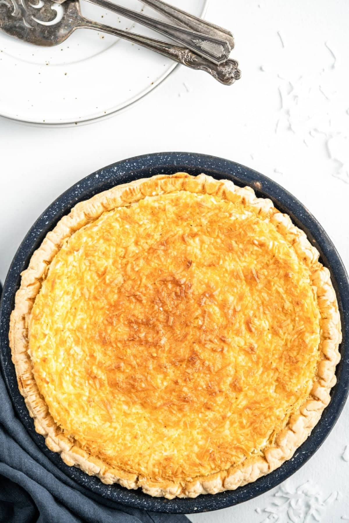 This Old Fashioned Coconut Custard Pie is rich, creamy and packed with sweet coconut flavor! 🥥 Made with a silky homemade custard and flaky pie crust, it's the perfect dessert for Thanksgiving, Easter, Christmas or Sunday dinner. Save this classic pie recipe! #coconutcustardpie #pierecipes #dessertrecipes #oldfashionedrecipes #holidaydesserts Coconut Custard Pie just out of the oven