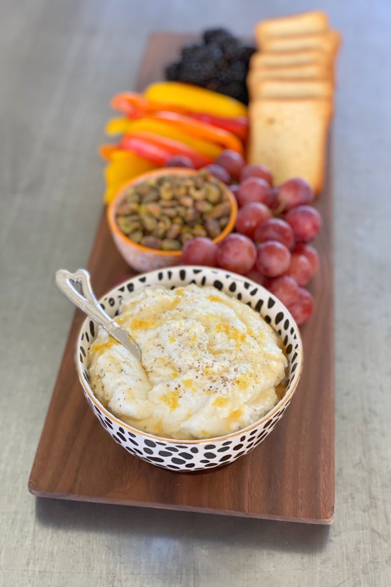 whipped goat cheese and ricotta dip on a board with nuts, veggies and fruit