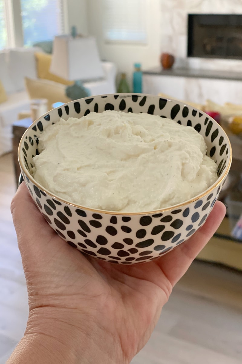 hand holding bowl of goat cheese and ricotta dip