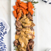 pot roast with gravy and carrots on a white platter