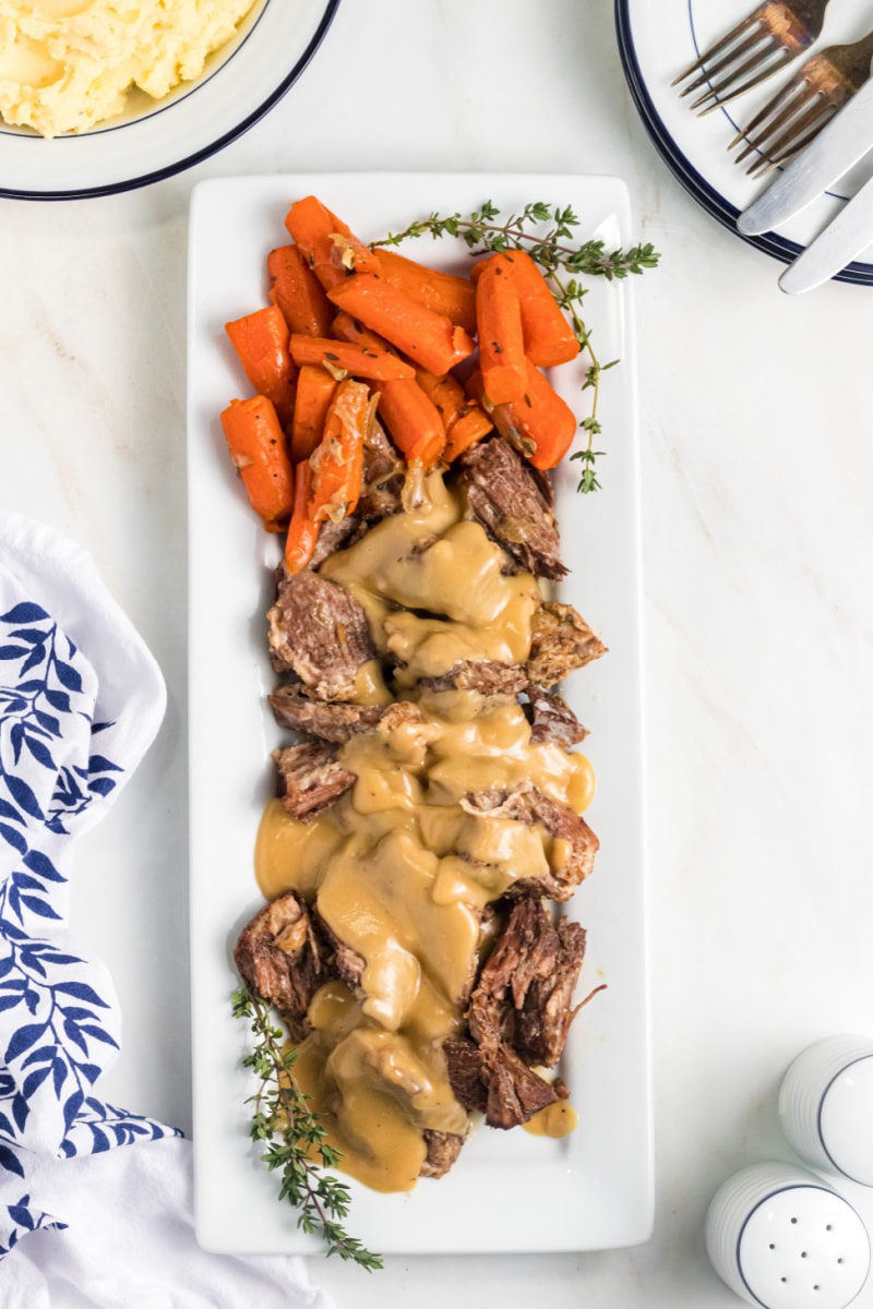 pot roast with gravy and carrots on a white platter