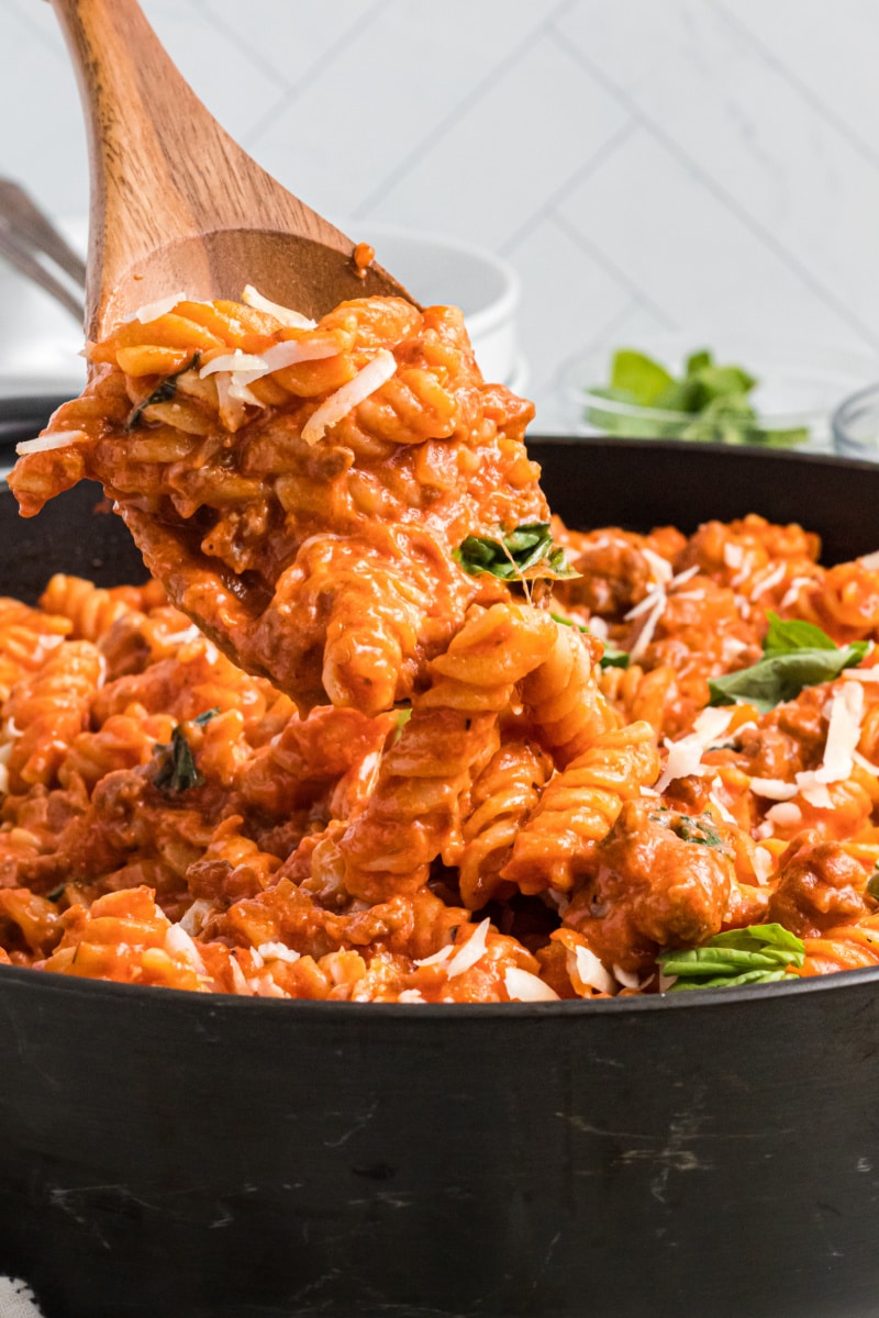 spooning out one pot sausage pasta out of skillet