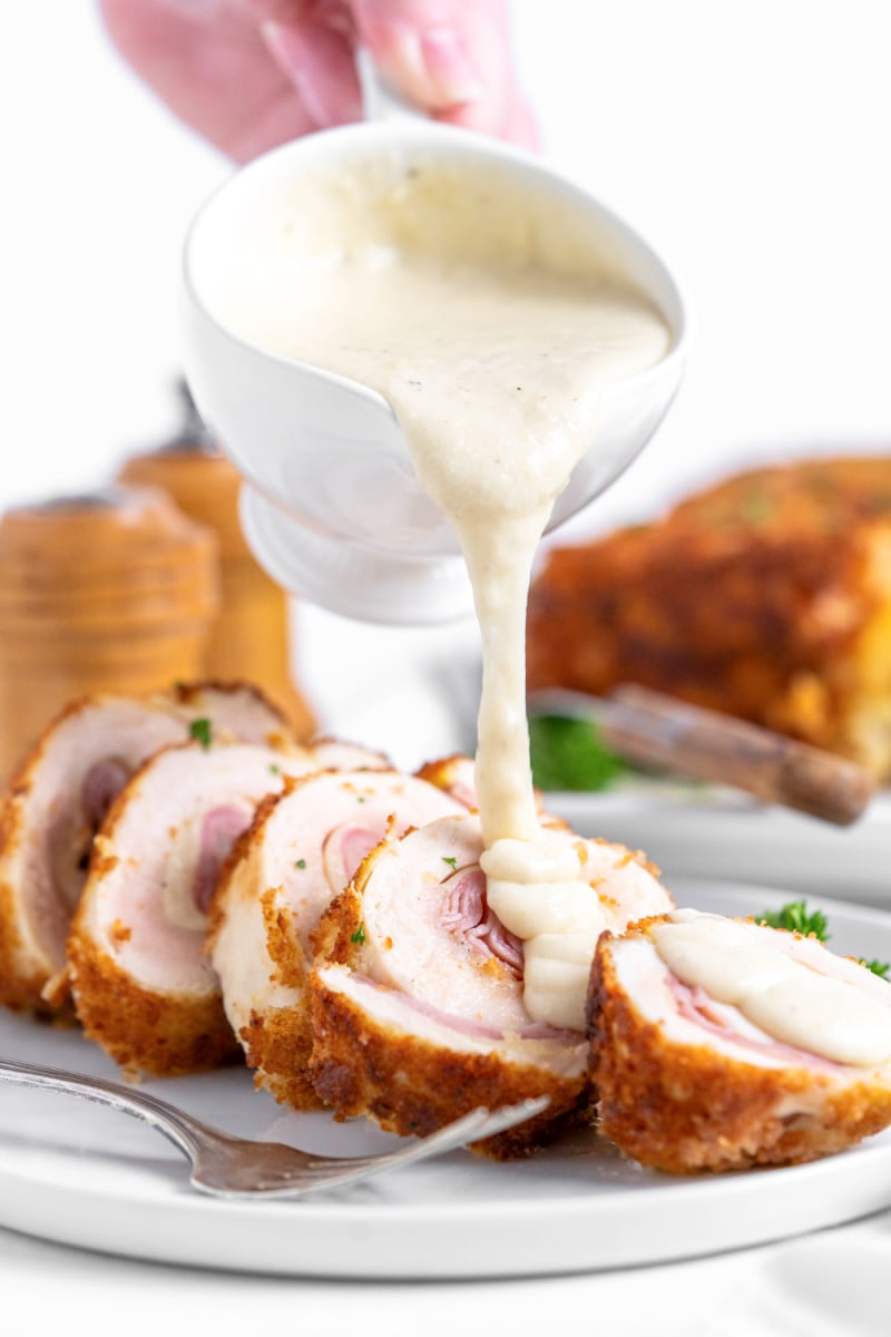 pouring sauce over chicken cordon bleu