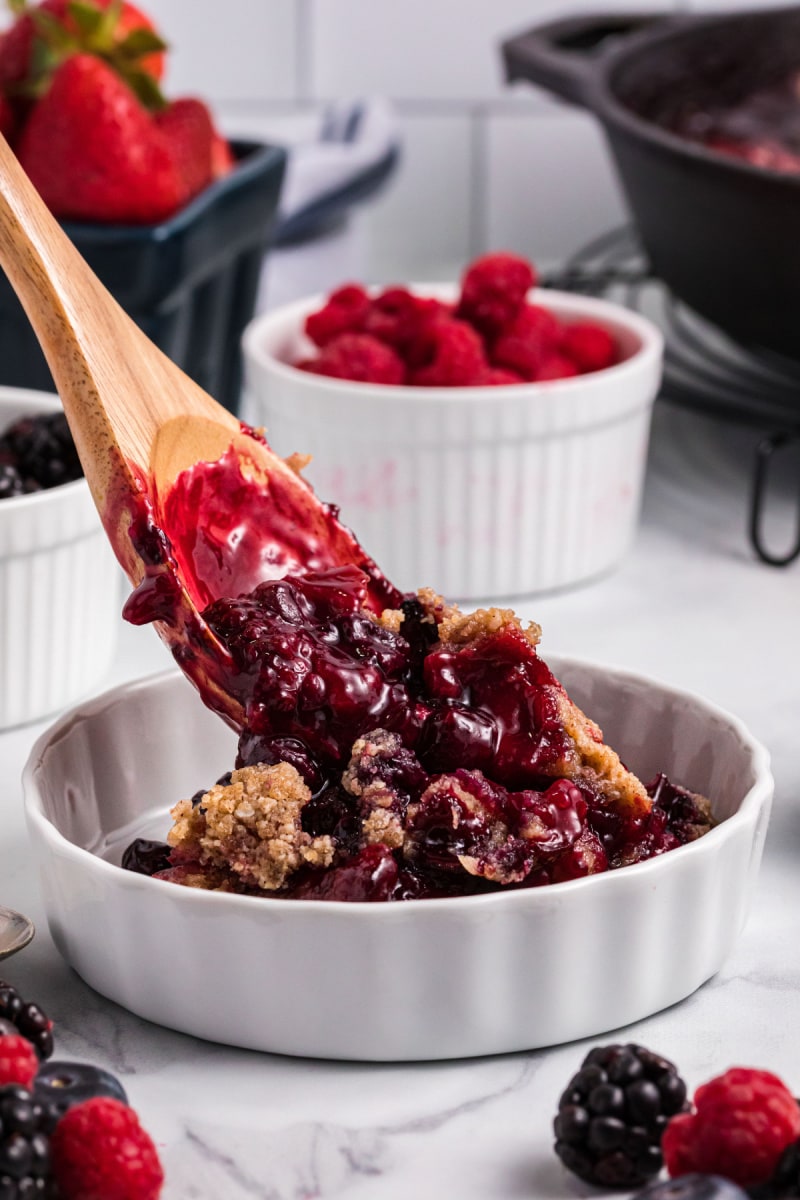 spooning berry crumble out of dish