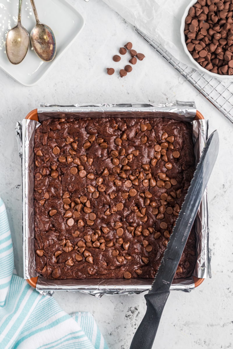chocolate overload brownies baked in a pan with a knife sitting on top