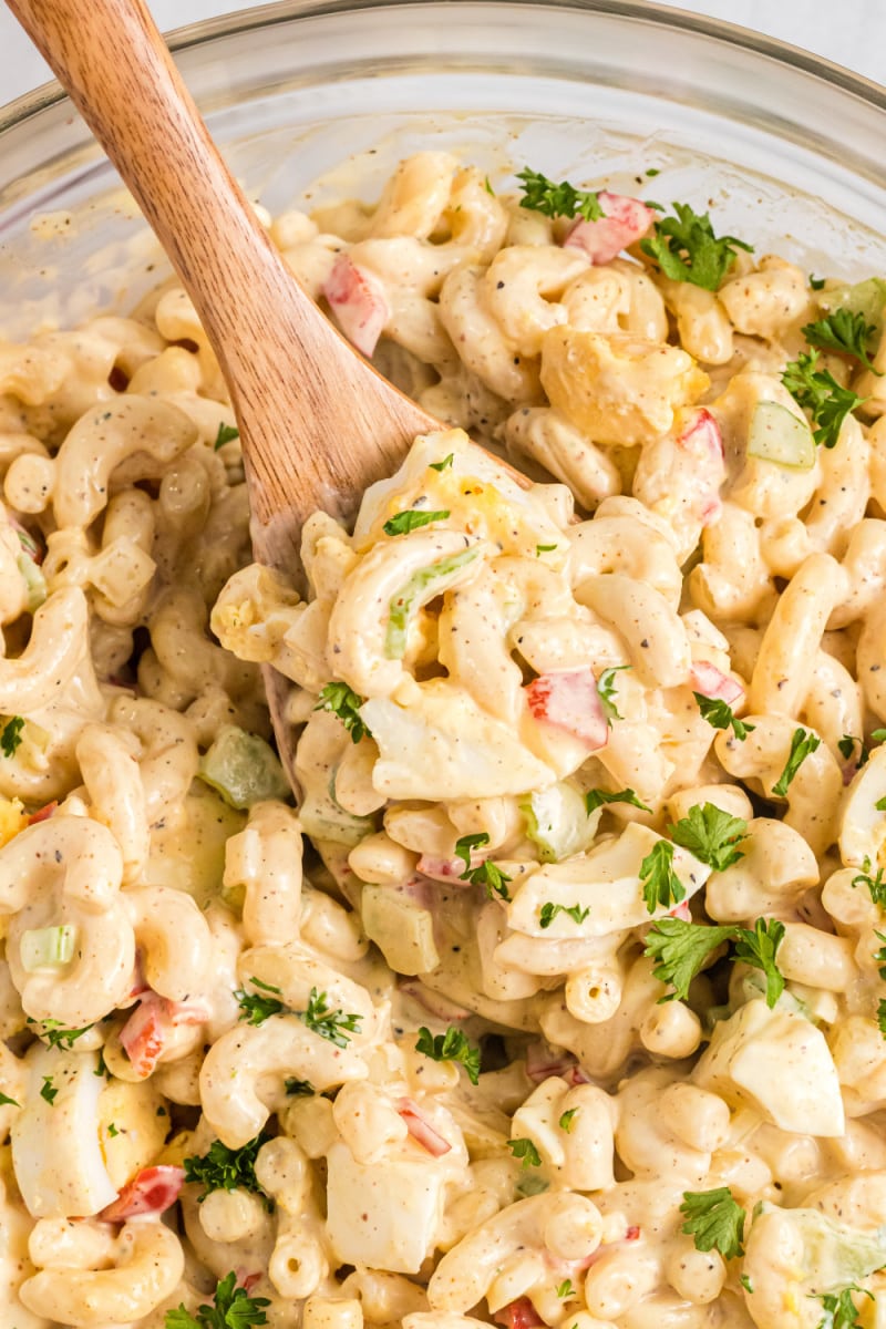 spooning macaroni salad out of bowl