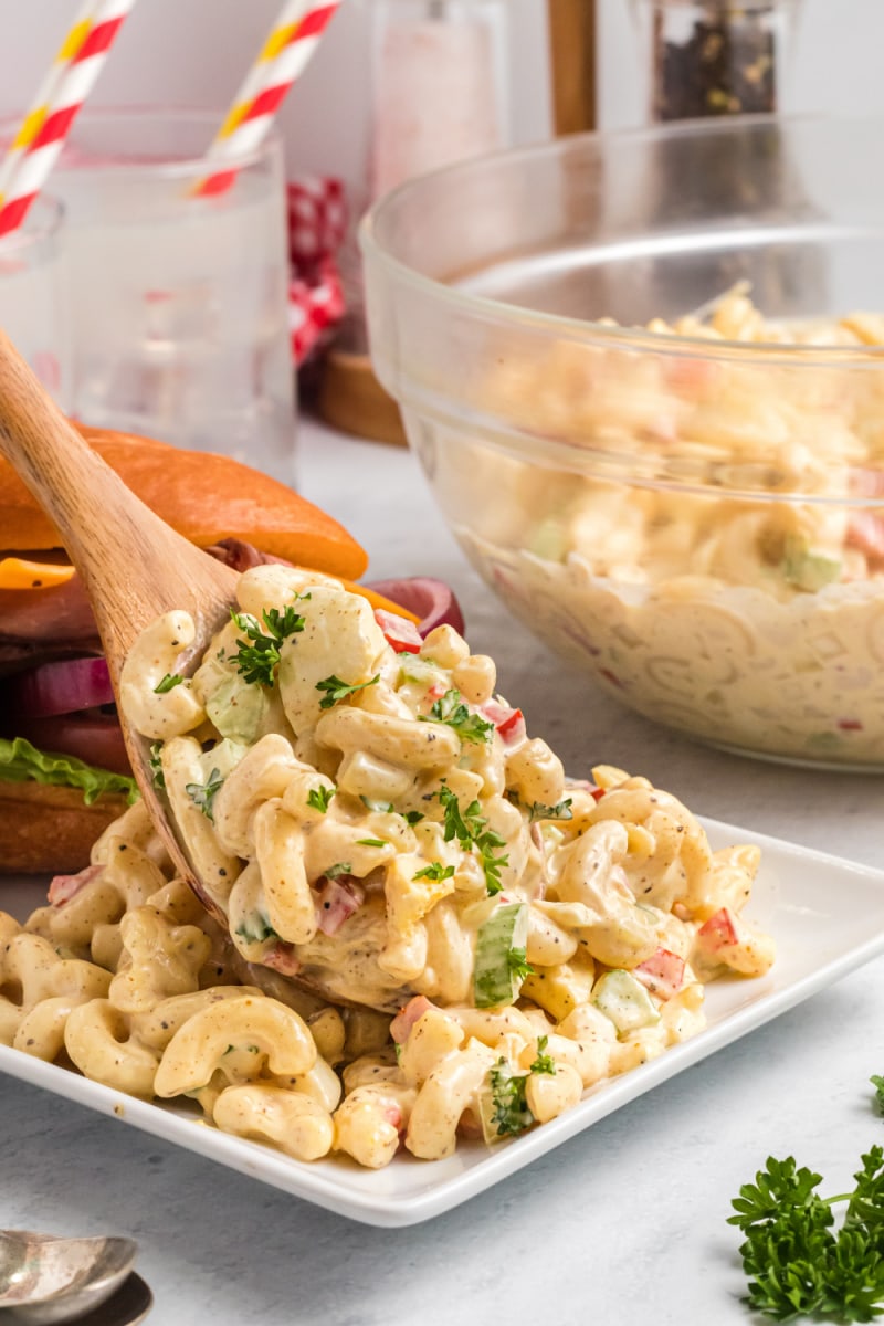 spooning macaroni salad onto a plate