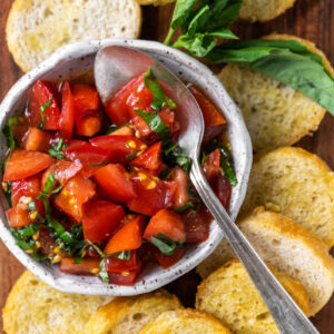 tomato bruschetta in bowl surrounded by baguette slices