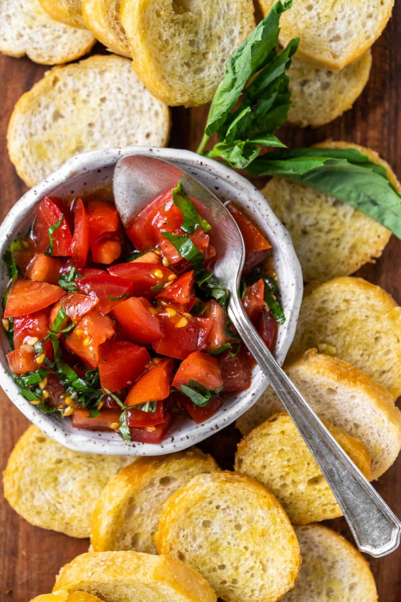 tomato bruschetta in bowl surrounded by baguette slices