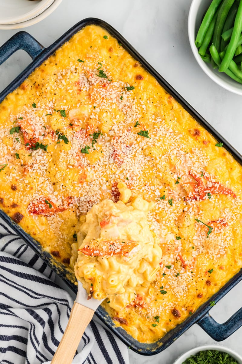 spooning out lobster macaroni and cheese out of baking dish