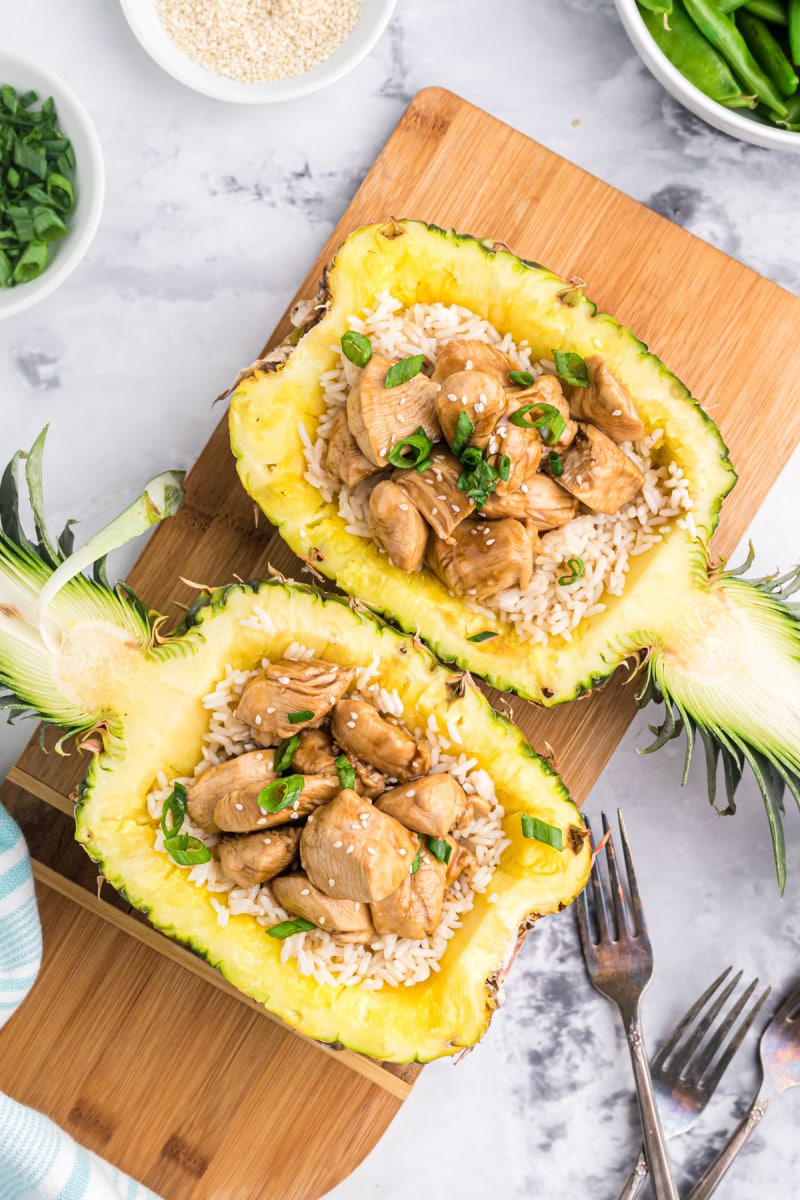 two pineapples hollowed out and stuffed with teriyaki chicken
