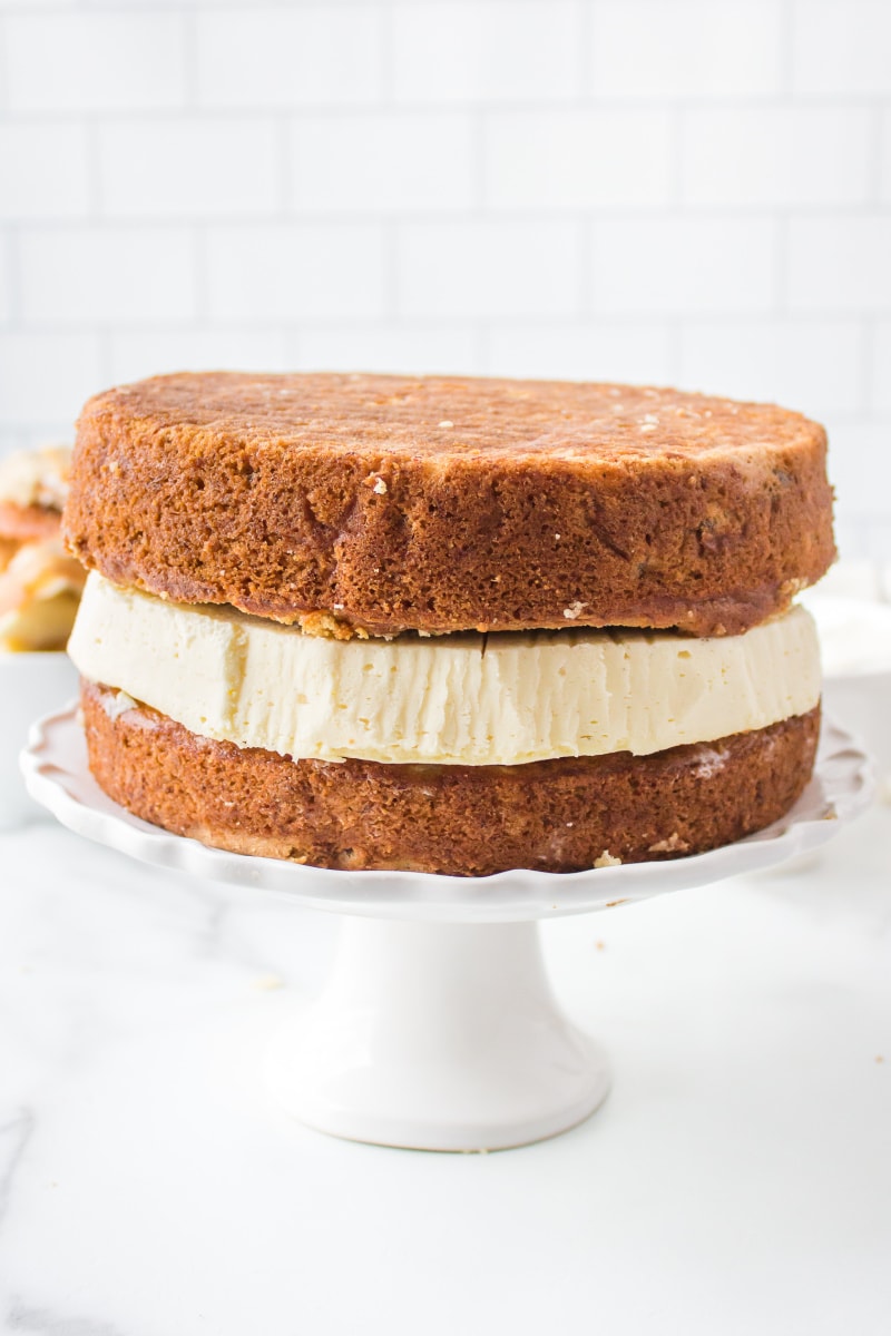 two layers of banana cake with cheesecake in the middle on cake platter