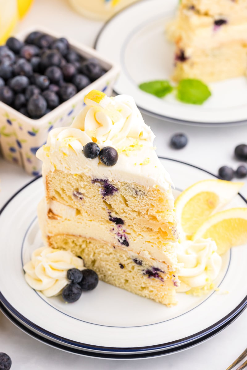 Blueberry Cheesecake Cake recipe from RecipeGirl.com #lemon #blueberry #cheesecake #cake #recipe #RecipeGirl slice of blueberry cheesecake cake on plate