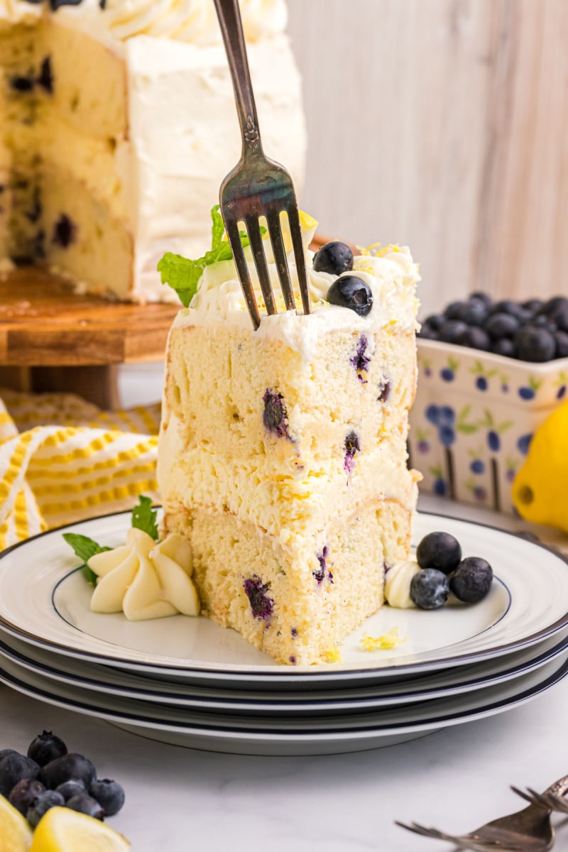 Blueberry Cheesecake Cake recipe from RecipeGirl.com #lemon #blueberry #cheesecake #cake #recipe #RecipeGirl fork in a slice of blueberry cheesecake cake