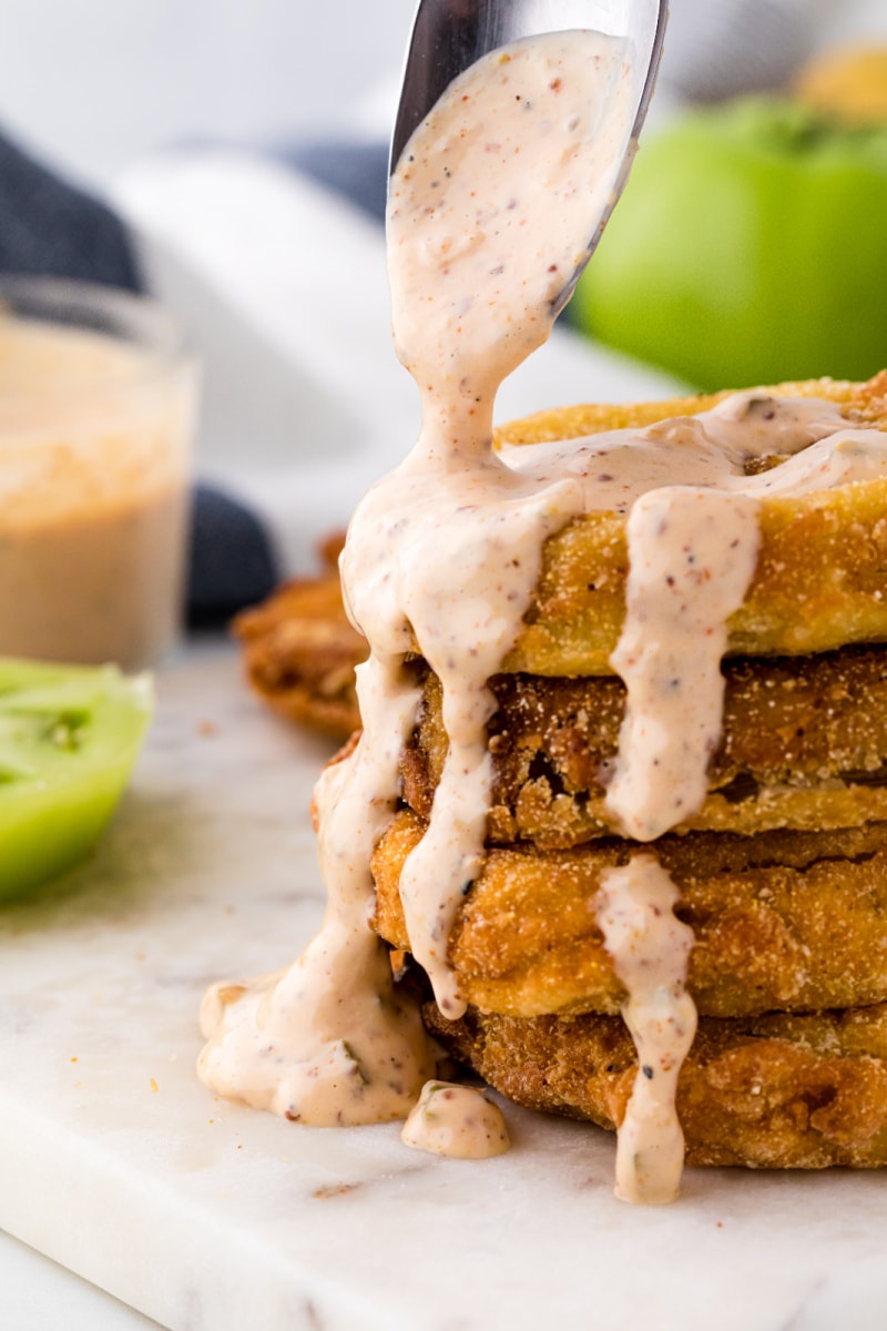 stack of fried green tomatoes with spooned remoulade sauce on top