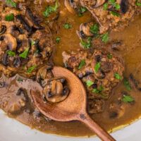 salisbury steak in a skillet with a wooden spoon