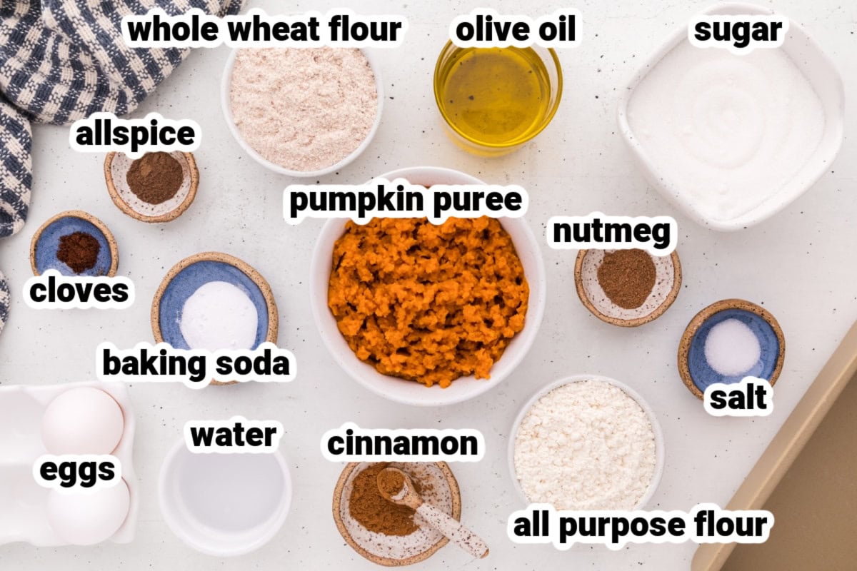This moist Whole Wheat Pumpkin Bread is made with olive oil, pumpkin puree, whole wheat flour, cinnamon, nutmeg and warm fall spices. It's an easy pumpkin bread recipe for breakfast, snacking, freezing or fall gifting. ingredients displayed for making whole wheat pumpkin bread