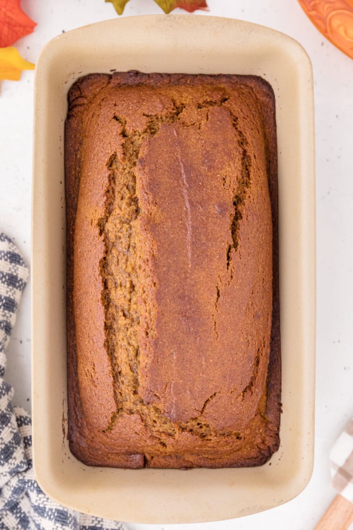 This moist Whole Wheat Pumpkin Bread is made with olive oil, pumpkin puree, whole wheat flour, cinnamon, nutmeg and warm fall spices. It's an easy pumpkin bread recipe for breakfast, snacking, freezing or fall gifting. whole wheat pumpkin bread loaf overhead shot