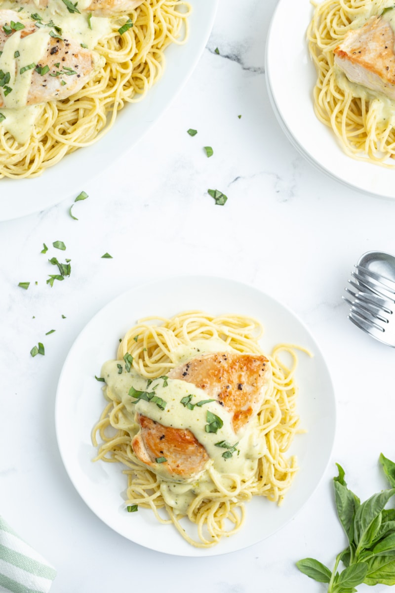 creamy pesto chicken over noodles on a plate