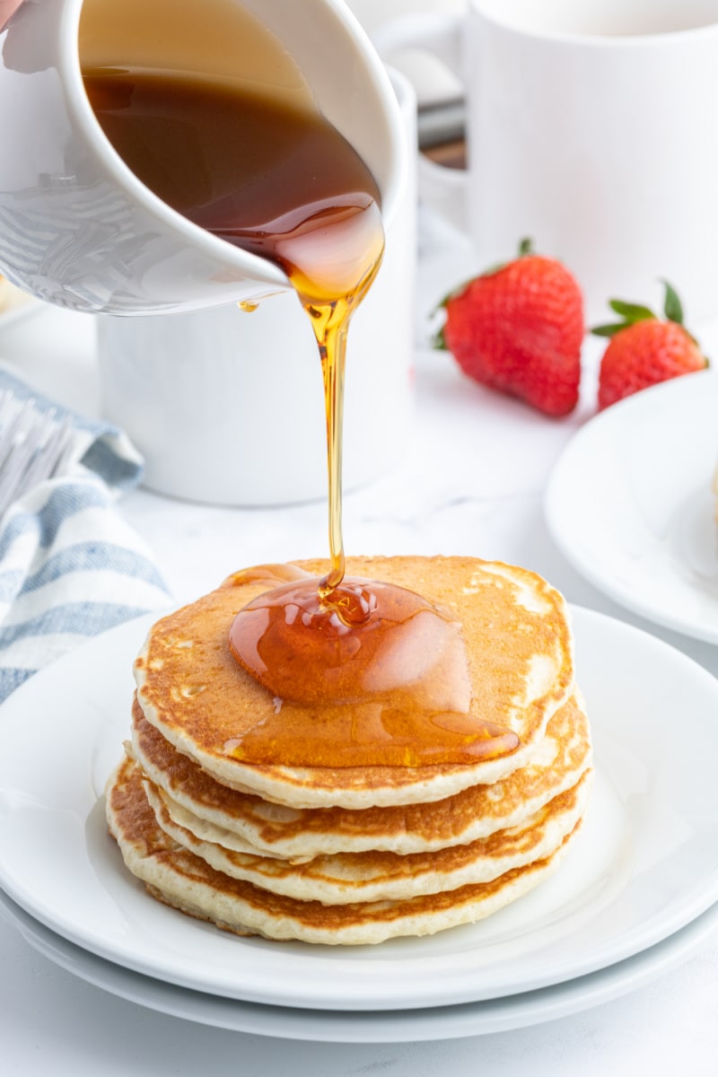 pouring syrup onto pancakes