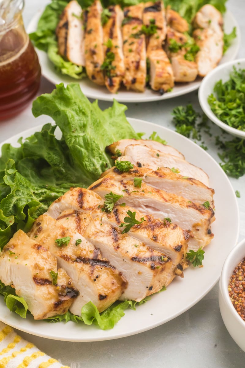sliced grilled chicken on plates with lettuce