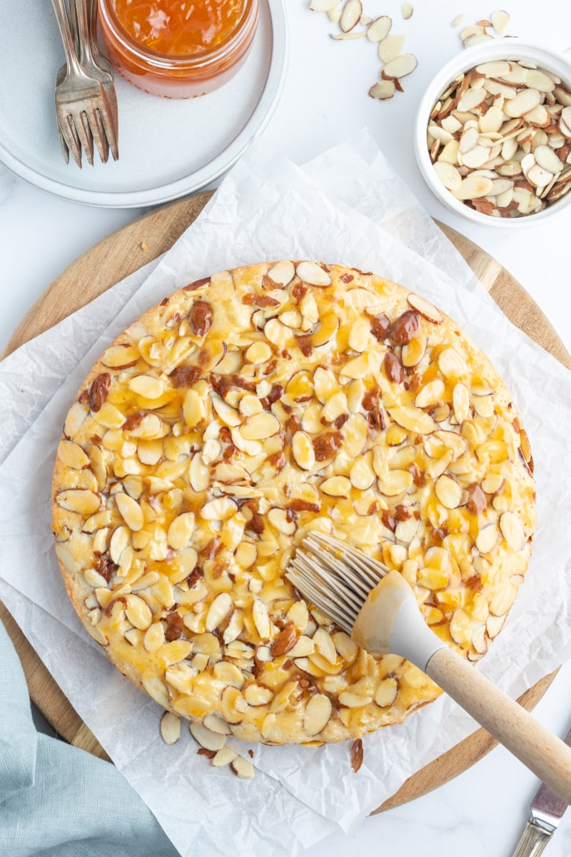 brushing jam onto french almond cake