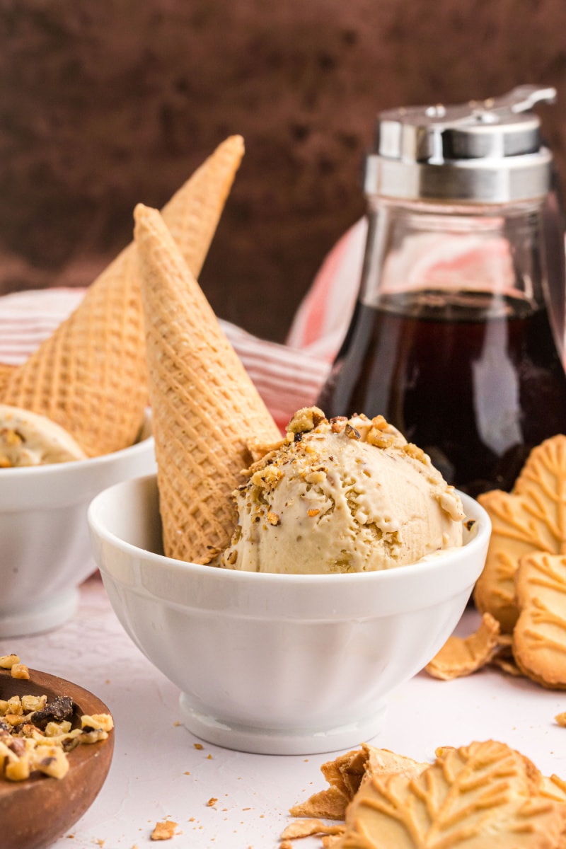 scoop of maple walnut ice cream on a sugar cone in a bowl
