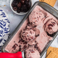 pan of cherry cheesecake ice cream with scoops on top and scooper