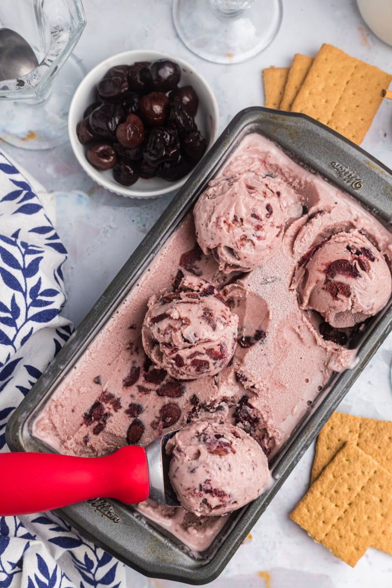 pan of cherry cheesecake ice cream with scoops on top and scooper