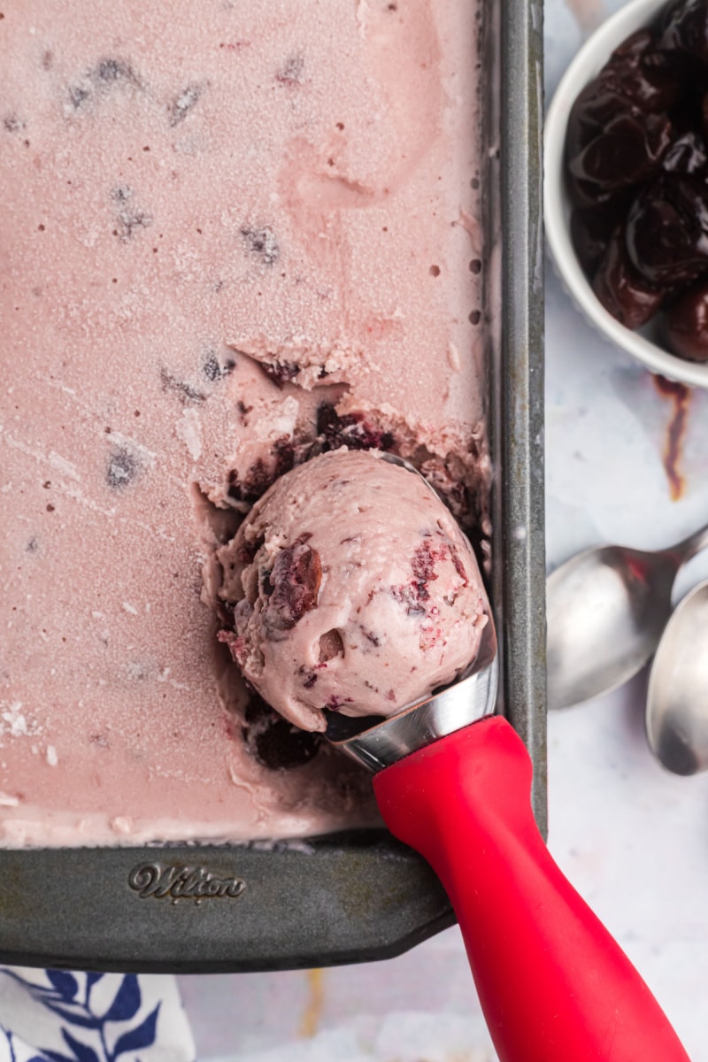 cherry cheesecake ice cream in a pan with a scoop