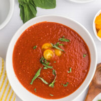 bowl of chilled tomato soup garnished with tomato and basil
