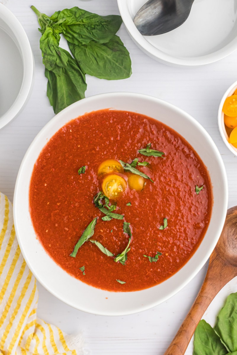 bowl of chilled tomato soup garnished with tomato and basil